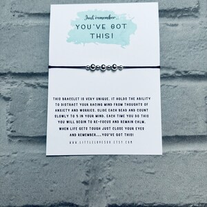 May include: A black string bracelet with silver beads. The card attached to the bracelet reads "Just remember... YOU'VE GOT THIS!" and explains how to use the bracelet to help with anxiety and worries. The card also includes the website www.littlelovesho.etsy.com.