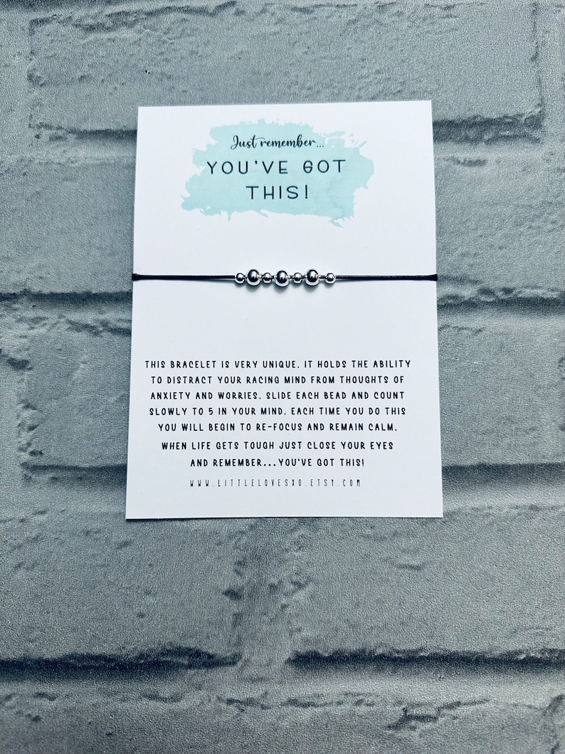 May include: A black string bracelet with silver beads. The card attached to the bracelet reads "Just remember... YOU'VE GOT THIS!" and explains how to use the bracelet to help with anxiety and worries. The card also includes the website www.littlelovesho.etsy.com.