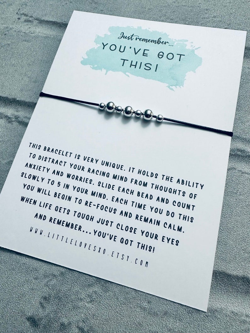 May include: A black string bracelet with silver beads. The bracelet comes with a card that reads "Just remember... YOU'VE GOT THIS!" and includes instructions on how to use the bracelet to help with anxiety and worries.