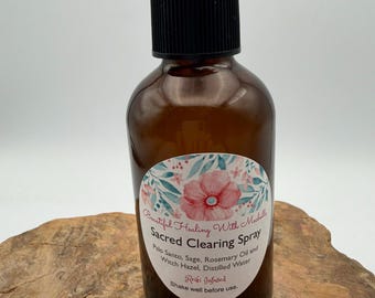 May include: A brown glass spray bottle with a black pump top. The label features a floral design with pink flowers and green leaves, reading: Beautiful Healing With Michelle Sacred Clearing Spray, Palo Santo, Sage, Rosemary Oil and Witch Hazel, Distilled Water, Reiki Infused, Shake well before use.