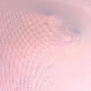 May include: A soft, pink, dotted fabric, possibly a textile or a protective covering. The material appears to be stretched or draped, with subtle shadows and variations in color.