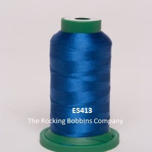 May include: A spool of blue thread with a green top and bottom. The spool is labeled "ES413" and "The Rocking Bobbins Company".