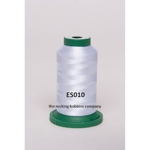 May include: A white spool of thread with a green top and bottom. The spool is labeled "ES010 the rocking bobbins company".