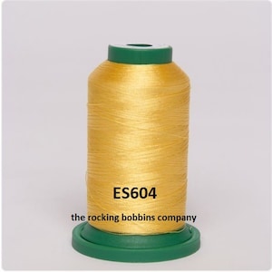 May include: A spool of yellow thread with a green top and bottom. The spool is labeled "ES604" and "the rocking bobbins company".