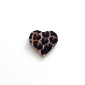 Peut inclure: Un écusson en forme de cœur avec un motif léopard marron et noir. L'écusson est posé sur un fond blanc uni, mettant en valeur sa forme et son motif. Ce patch décoratif pourrait être utilisé pour les vêtements ou l'artisanat.