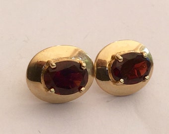 May include: A pair of gold earrings with oval-shaped red gemstones.