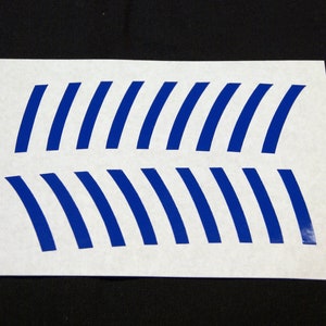 May include: A sheet of white paper with 16 blue curved lines arranged in two rows. The lines are evenly spaced and are all the same size and shape.