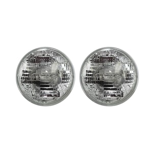 May include: Two round, silver, car headlights with a clear glass lens.