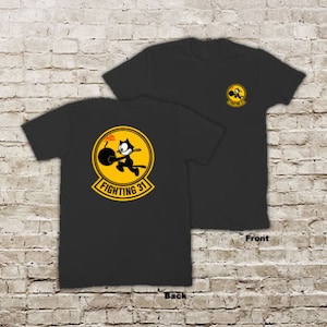 Könnte beinhalten: Schwarze T-Shirts mit einer Grafik einer Zeichentrickkatze, die eine Bombe hält, in einem gelben Kreis mit dem Text "FIGHTING 31". Die Vorderseite des T-Shirts hat eine kleinere Version derselben Grafik.