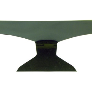 Può includere: Un'incudine in metallo nero con una parte superiore piatta e una base larga. L'incudine è realizzata in un unico pezzo di metallo e ha una finitura liscia e lucida.