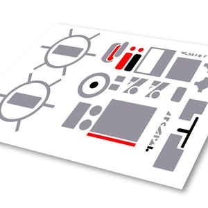 Op de afbeelding: Een vel met grijze en rode stickers met verschillende vormen en symbolen, waaronder cirkels, vierkanten, rechthoeken en een klein zwart-wit oog. De tekst "remarkable" is in wit op een grijze rechthoek gedrukt.