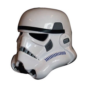 May include: A white plastic Star Wars Stormtrooper helmet with black and gray details. The helmet has a visor and a black band across the forehead.