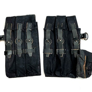 Puede incluir: Dos bolsas de lona negras con múltiples compartimentos y correas de cuero. Cada bolsa tiene un pequeño bolsillo separado en el lateral.