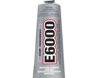 Op de afbeelding: Een zilveren tube met E6000 industriële lijm van industriële sterkte met een witte dop. De tube is gelabeld met "Helder - Transparant" en "Industriële sterkte lijm". De tube bevat 3,7 fl oz (109,4 ml) lijm.