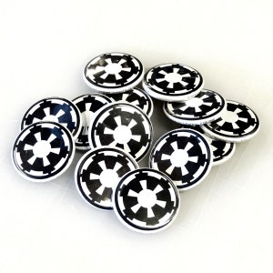 May include: A group of 12 white and black round buttons with the Star Wars Imperial symbol. The buttons are arranged in a circular pattern.