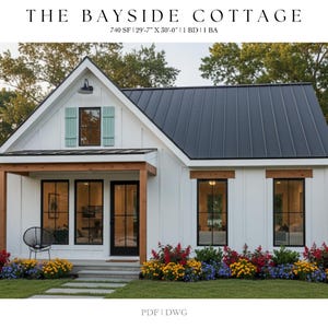 Op de afbeelding: Een wit huisje met een zwart dak en zwart omlijste ramen. Het huis heeft een kleine veranda met een houten balk en een zwarte deur. De tekst "THE BAYSIDE COTTAGE" staat bovenaan. Het huis is omgeven door kleurrijke bloemen.