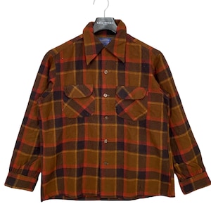 以下が含まれることがあります： 茶色、オレンジ、黒の格子柄のロングスリーブのチェックシャツ。シャツはボタンダウンカラーで、胸にポケットが2つ付いています。