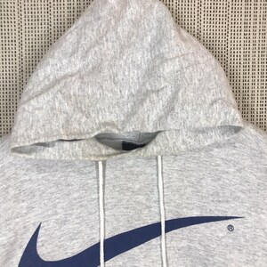 Peut inclure: Sweat-shirt &agrave; capuche gris avec un grand logo Nike swoosh bleu marine sur le devant. Le swoosh est soulign&eacute; de blanc.