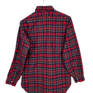 Puede incluir: Camisa de franela a cuadros rojos y verdes con mangas largas y cuello abotonado.