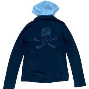 May include: Black zip-up hoodie with a gray hood. The back features a skull and crossbones design and the text "semantic design" embroidered in a matching color. A casual, edgy style.