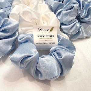 May include: A collection of light blue and white satin scrunchies. A tag reads "Dearest Gentle Reader Society Papers AMANDA BRIDAL SHOWER". The scrunchies are gathered and appear soft and silky. Ideal for hair accessories or bridal party favors.