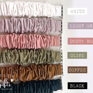May include: Six different colored Apple Watch bands made of a soft, stretchy fabric. The colors are white, light gray, dusty rose, olive, coffee, and black.