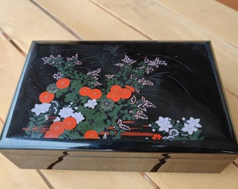 Black lacquered music box with leaf and flower design made in Japan around 1970 plays a melodic sound