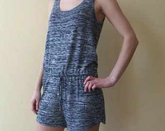 Op de afbeelding: Een grijs en wit gestreepte, mouwloze jumpsuit met een trekkoord in de taille.