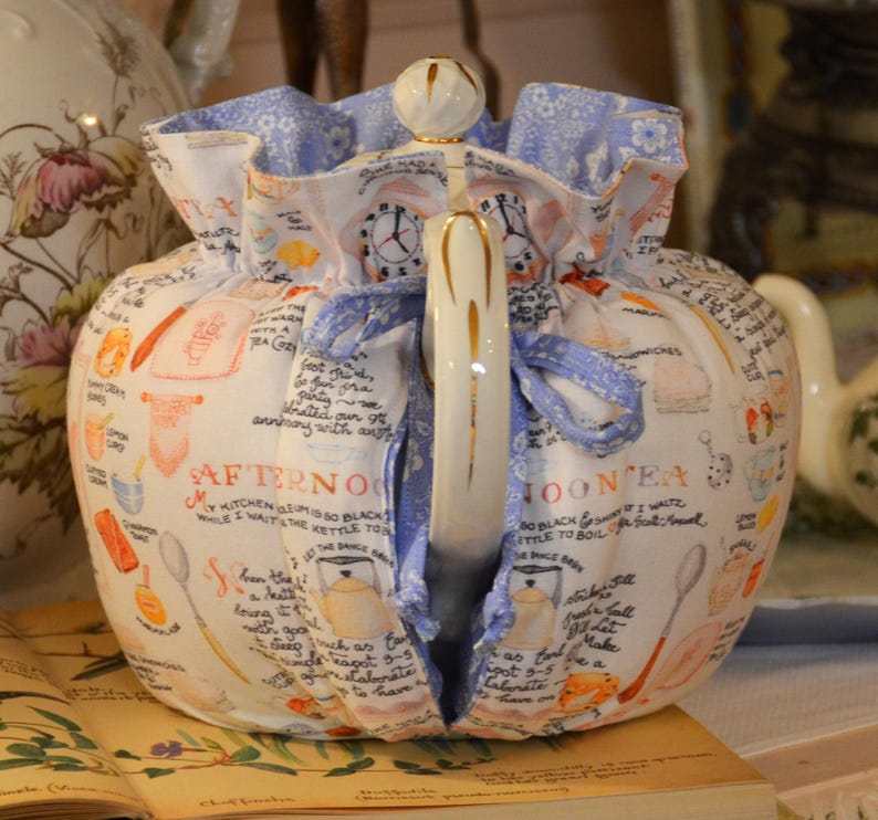 Może przedstawiać: Biały ceramiczny kubek z czarnym uchwytem i napisem "But First, Coffee" czarną, pogrubioną czcionką. Kubek stoi na drewnianej powierzchni.