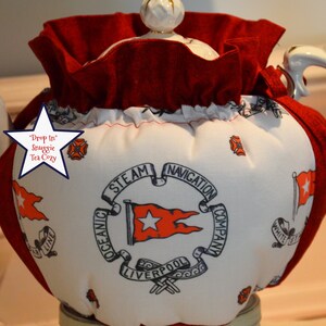 Puede incluir: Calienta tazas rojo y blanco con un dise&ntilde;o n&aacute;utico que presenta una bandera roja con una estrella blanca y el texto "Oceanic Steam Navigation Company Liverpool".