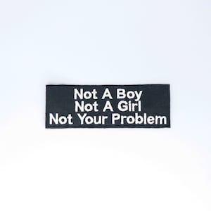 May include: Black embroidered patch with white text that reads "Not A Boy Not A Girl Not Your Problem".