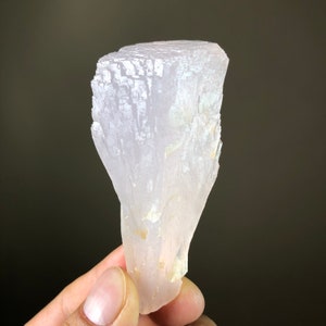 May include: A translucent, pale pink crystal with a layered, fan-shaped structure. The crystal is smooth and has a slightly iridescent sheen.