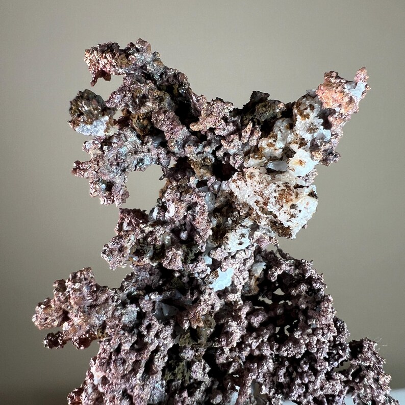 Pode incluir: Uma imagem detalhada de um esp&eacute;cime mineral de cobre. O esp&eacute;cime tem uma superf&iacute;cie complexa e texturizada com uma mistura de tons castanho-avermelhados, cobre, branco e cinza. A forma &eacute; irregular e org&acirc;nica.