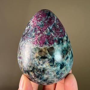 Puede incluir: Una gema pulida en forma de huevo con un patrón de remolino de rosa, verde y negro.