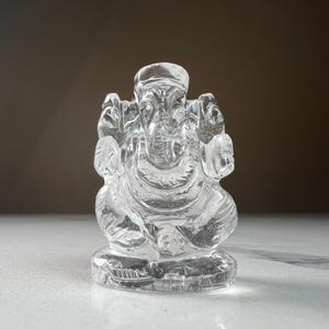 May include: A clear crystal sculpture of the Hindu deity Ganesha, the elephant-headed god of wisdom and prosperity.