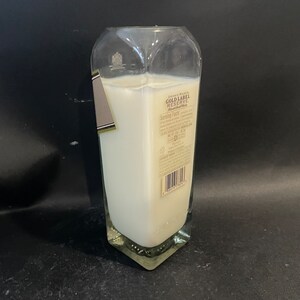 May include: A clear glass candle jar with a white candle inside. The jar is shaped like a liquor bottle and has a label that reads "Johnnie Walker Gold Label Reserve Blended Scotch Whisky".