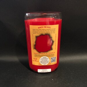 May include: A red glass candle jar with a gold label that reads "Ignite the Nite" and "Cinnamon". The label also includes the text "What you have here is smooth whiskey with a fiery kick of red hot cinnamon. It tastes like heaven, burns like hell. What happens next is up to you."