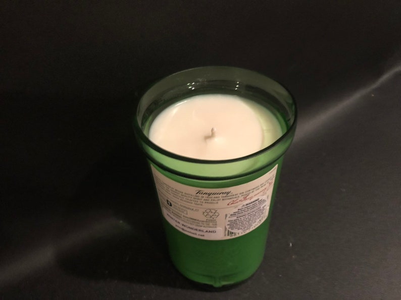 May include: A green glass candle jar with a white candle inside. The jar has a label that says "Tanqueray" and "London Dry Gin".