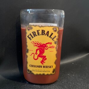 May include: A glass bottle with a red liquid inside. The bottle has a yellow label with the words "Fireball", "Red", "Hot", "Cinnamon Whisky", "ALC 33% BY VOL 166 PROOF", and "WHISKEY WITH NATURAL CINNAMON FLAVOR".