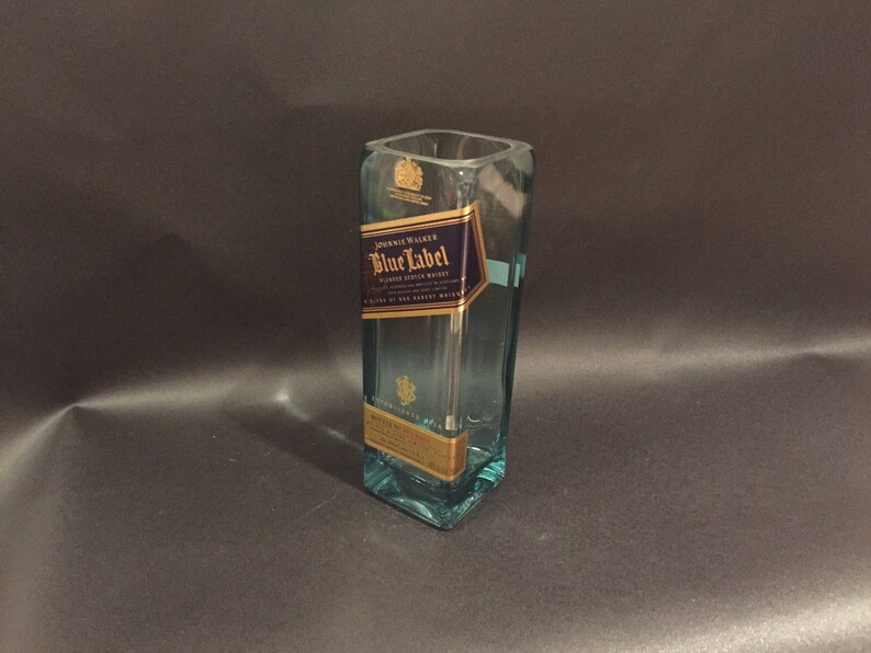 May include: A repurposed Johnnie Walker Blue Label bottle, now a vase. The clear glass vessel features the original label with gold and navy blue details. The square shape and label are clearly visible. A unique upcycled item.