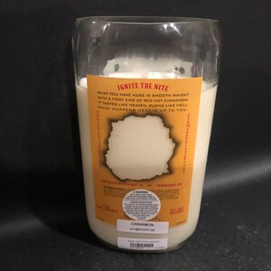 May include: A clear glass bottle candle with a white label that reads "Ignite the Nite" and "What you have here is smooth whisky with a fiery kick of red hot cinnamon. It tastes like heaven, burns like hell. What happens next is up to you." The label also includes the text "Cinnamon" and "info@fireballwhisky.com".