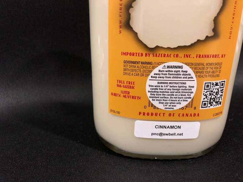 May include: A yellow and white candle jar with a cinnamon scent. The jar has a black label with the text "Cinnamon" and "pnc@swbell.net". The jar also has a yellow label with the text "Product of Canada" and a warning label with instructions for burning the candle safely.
