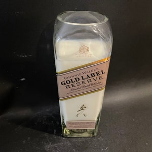 May include: A white candle in a clear glass bottle with a gold label that reads "JOHNNIE WALKER GOLD LABEL RESERVE Blended Scotch Whisky".