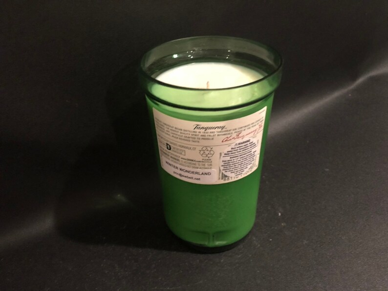 May include: A green glass candle jar with a white candle inside. The jar has a label that says "Tanqueray" and "Winter Wonderland".