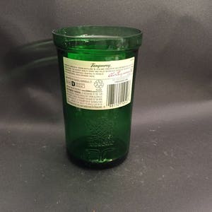 May include: A green glass bottle with a label that reads "Tanqueray" and "London Dry Gin". The bottle is empty and has a textured surface.
