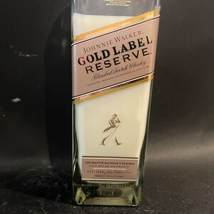 May include: A clear glass bottle with a white label that says "JOHNNIE WALKER. GOLD LABEL RESERVE. Blended Scotch Whisky DISTILLED, BLENDED AND BOTTLED IN SCOTLAND THE MASTER BLENDER'S RESERVE ESTT 1820 PRODUCT OF SCOTLAND"