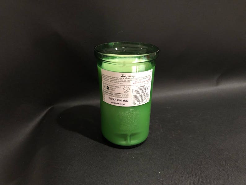 May include: A green glass candle jar with a white label that reads "Tangyberry Clean Cotton" and a recycling symbol.