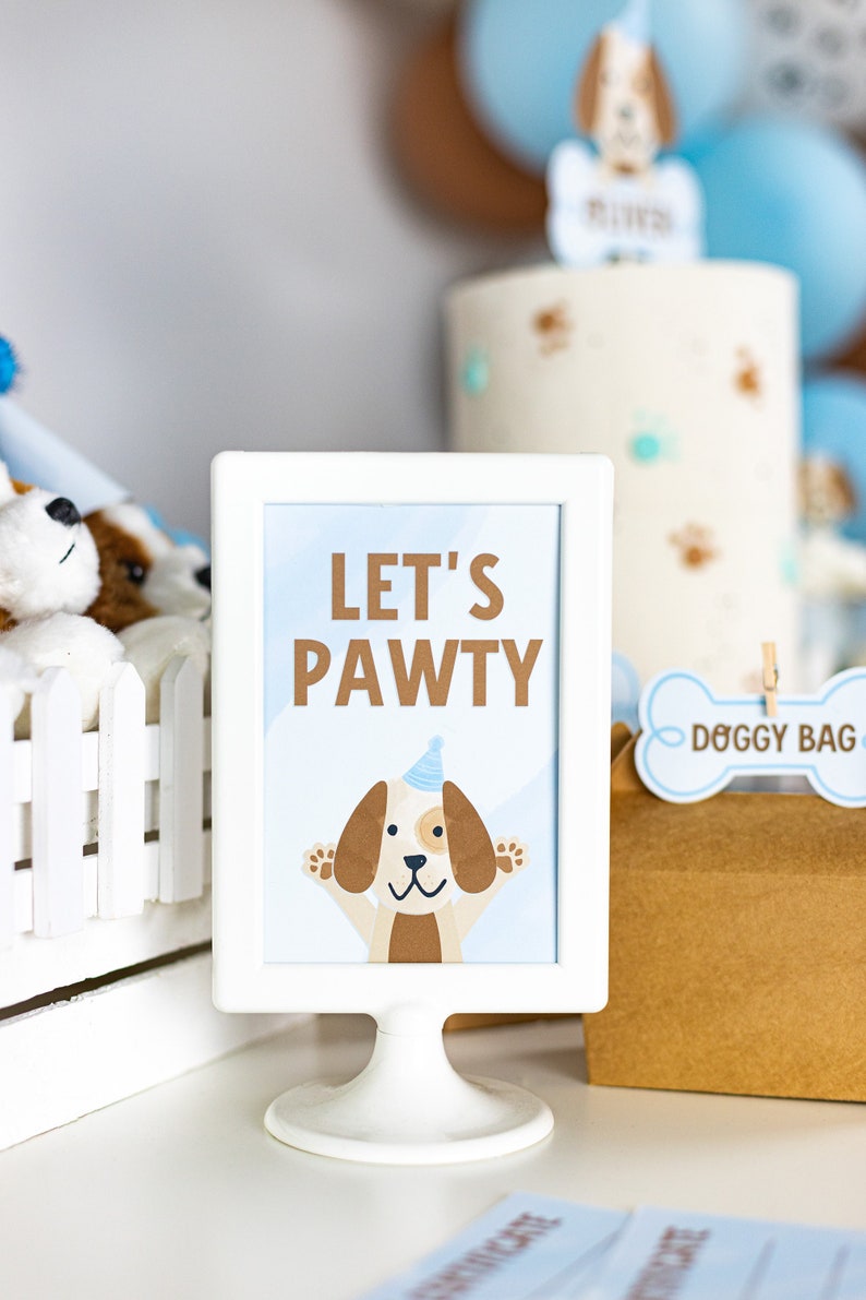 May include: White sign with a blue background and the text "Let's Pawty" in brown letters. A cartoon dog wearing a blue party hat is in the center of the sign.
