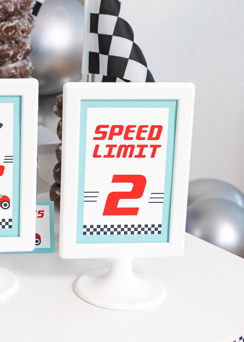 May include: White picture frame with a blue background and the text "Speed Limit 2" in red. The frame is on a white stand.