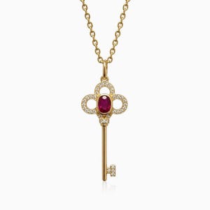 May include: A gold necklace featuring a key-shaped pendant. The pendant head is adorned with small white diamonds and a central oval-cut red ruby. The key shaft and bit are also accented with tiny white diamonds, suspended from a delicate gold chain.